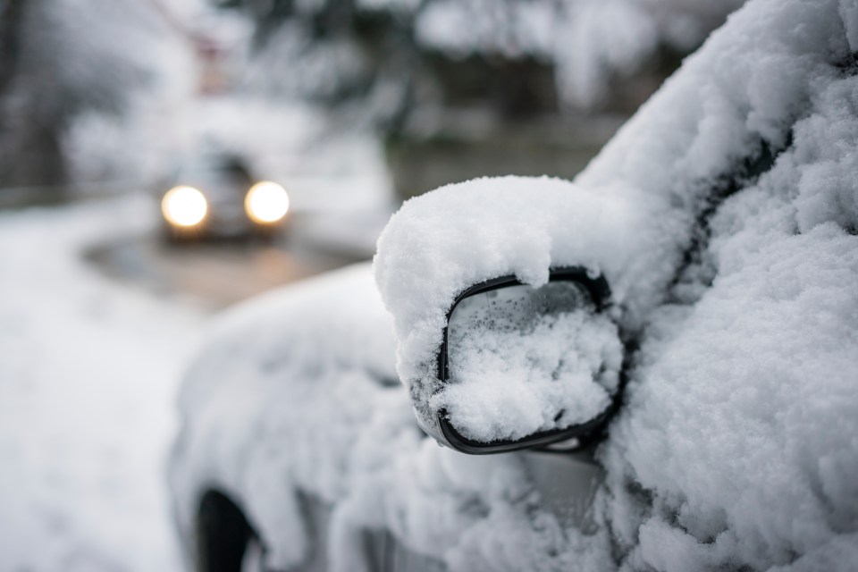 a car is covered in snow with a car in the background