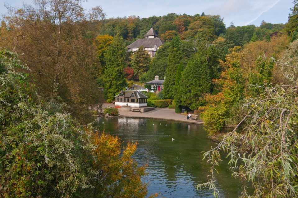 Lake in Grange over Sands park with autumn foliage and buildings in the background.