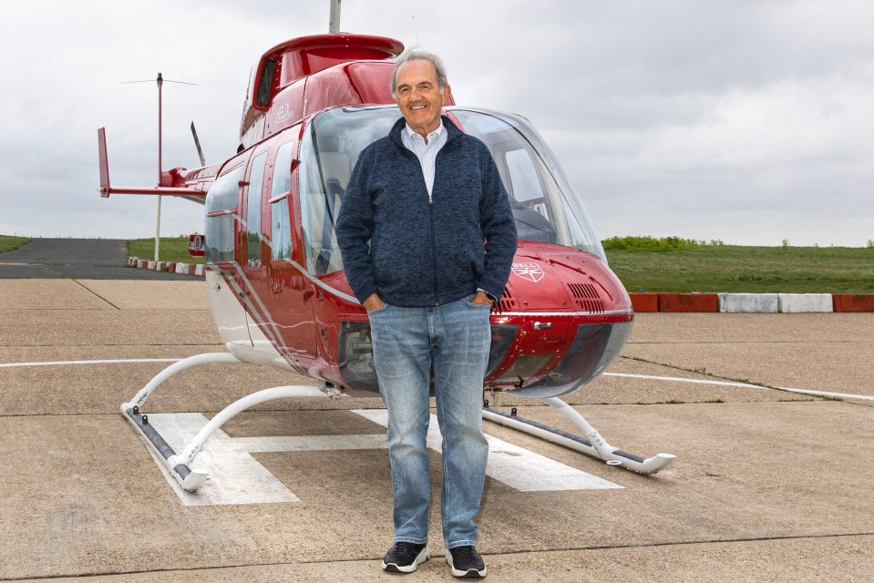 a man stands in front of a red helicopter that says ambulance