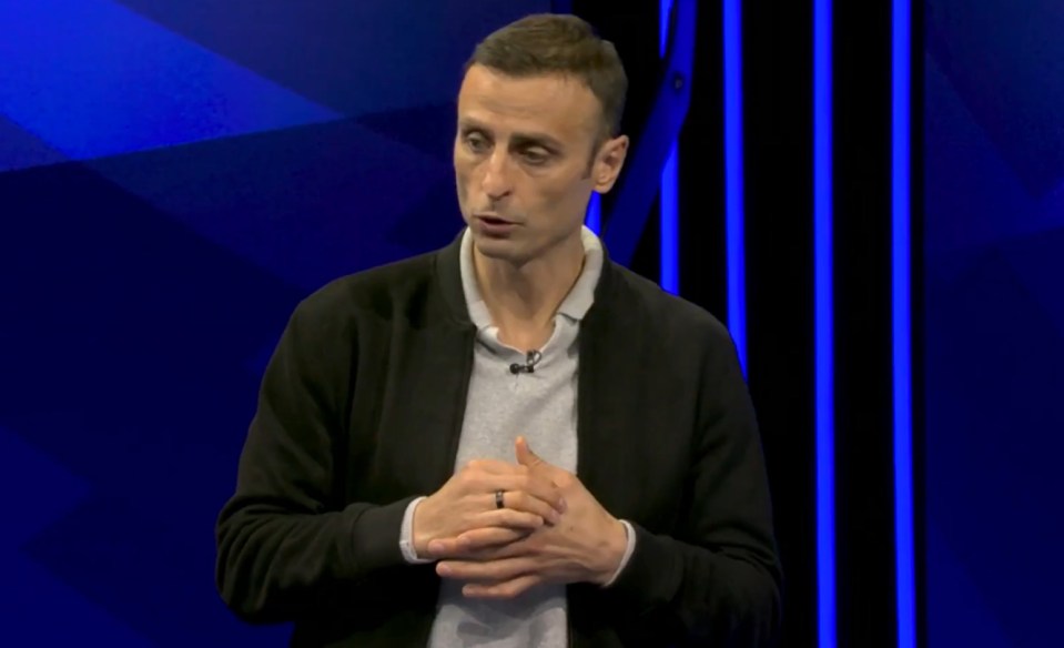 a man with a ring on his finger stands in front of a blue background