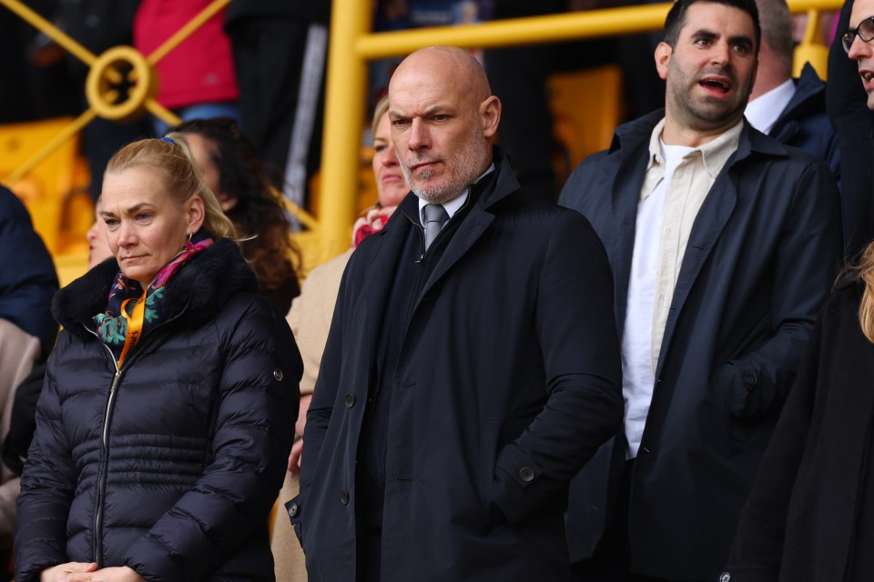 a man in a suit and tie stands next to a woman in a black jacket