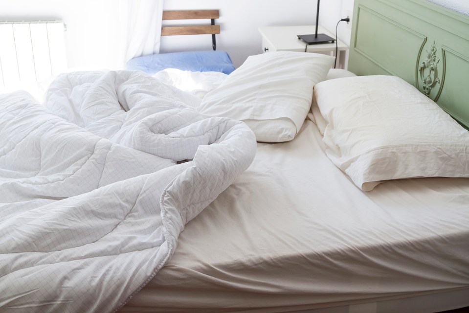 a bed with a white comforter and pillows on it