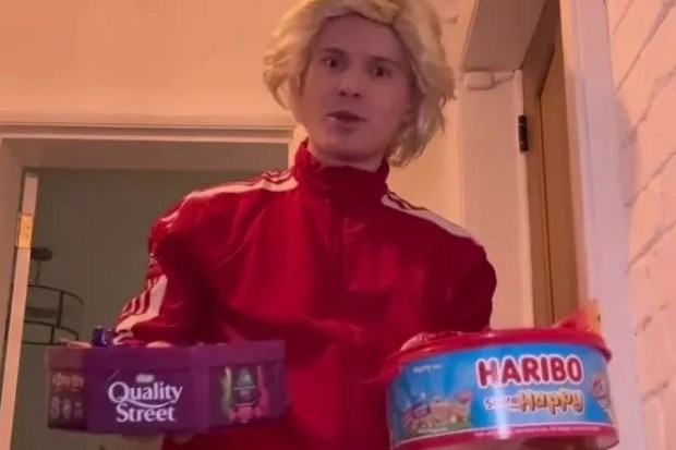 a man in a red jacket is holding a box of quality street and a box of haribo