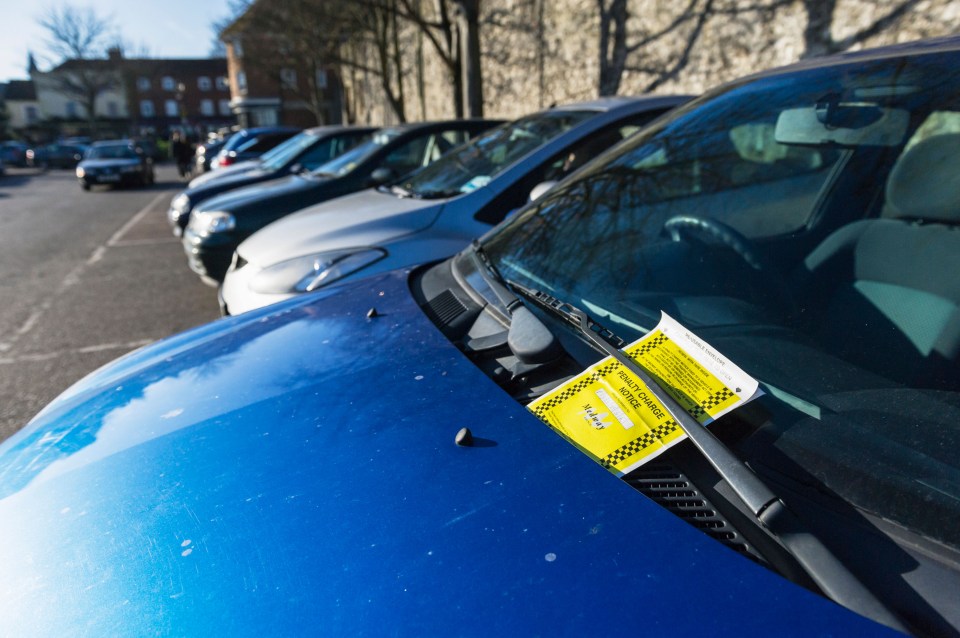 a blue car with a parking ticket on the windshield