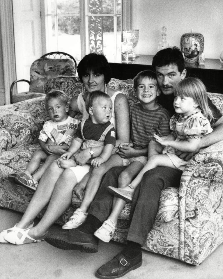 a black and white photo of a family sitting on a couch