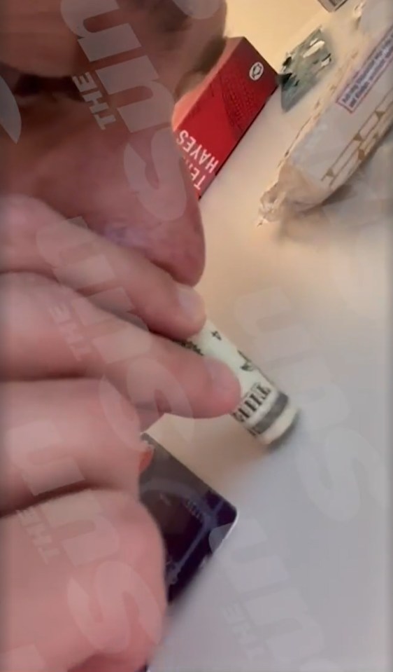 a person is holding a dollar bill in front of a box that says the sun