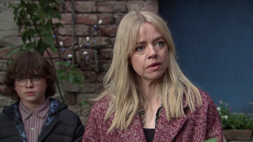 a woman and a boy are standing in front of a brick wall