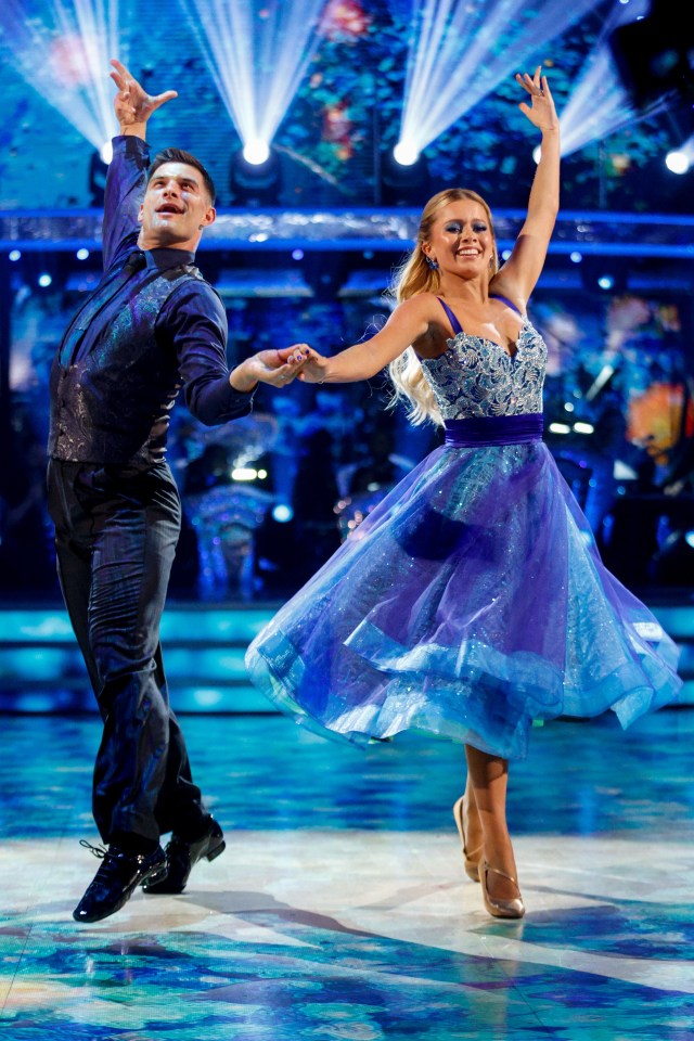 a man and a woman are dancing on a stage in front of a stained glass window