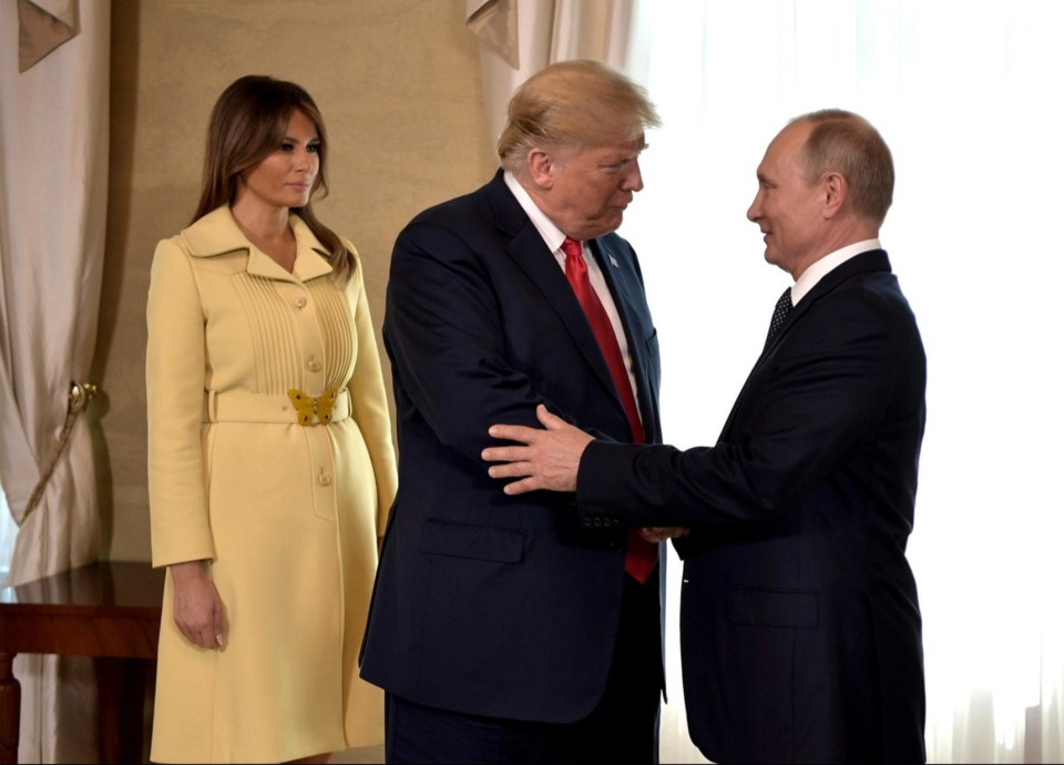 a woman in a yellow coat stands between two men in suits