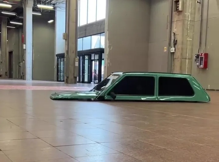 a green car is laying on the floor in an empty building