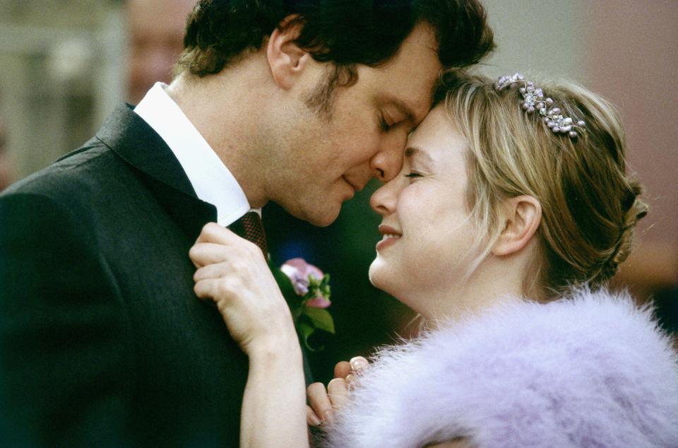a man kisses a woman on the forehead while wearing a purple fur coat
