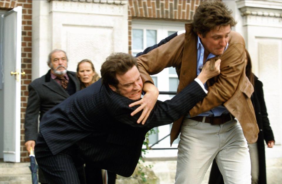 a man in a suit is being lifted by another man in a brown jacket