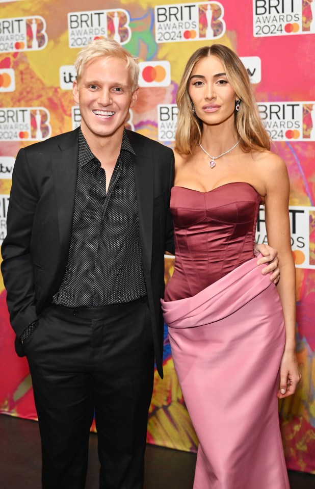 a man and a woman pose for a photo in front of a wall that says brit awards 2024