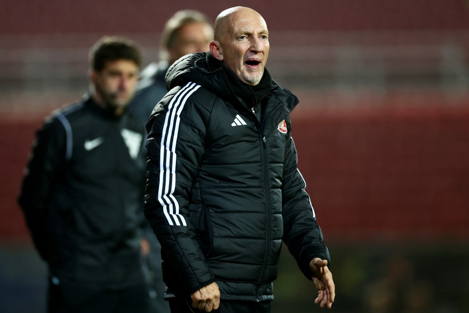a man wearing an adidas jacket stands on a soccer field
