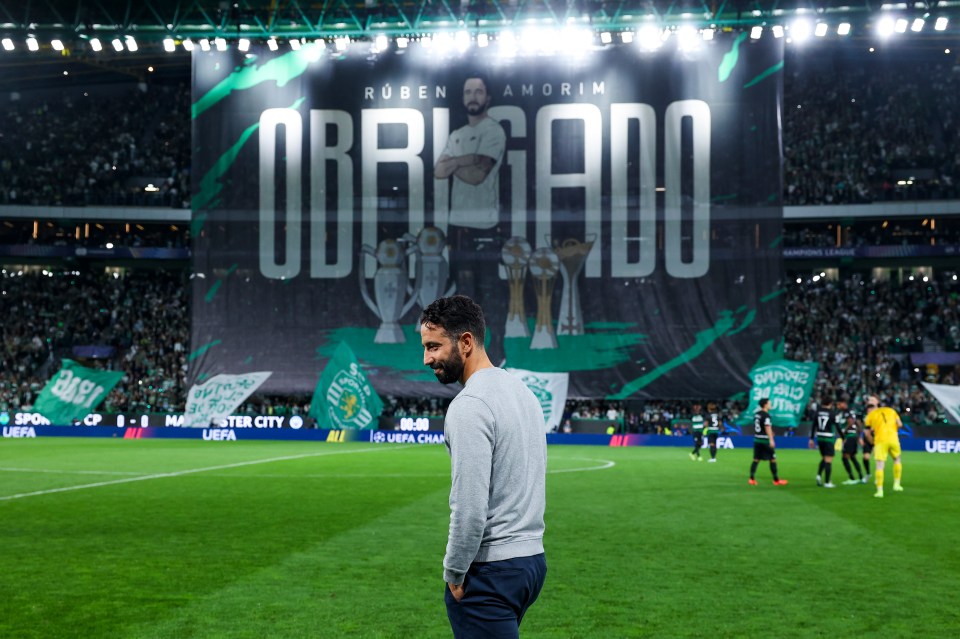 a man stands on a soccer field in front of a banner that says obrigado