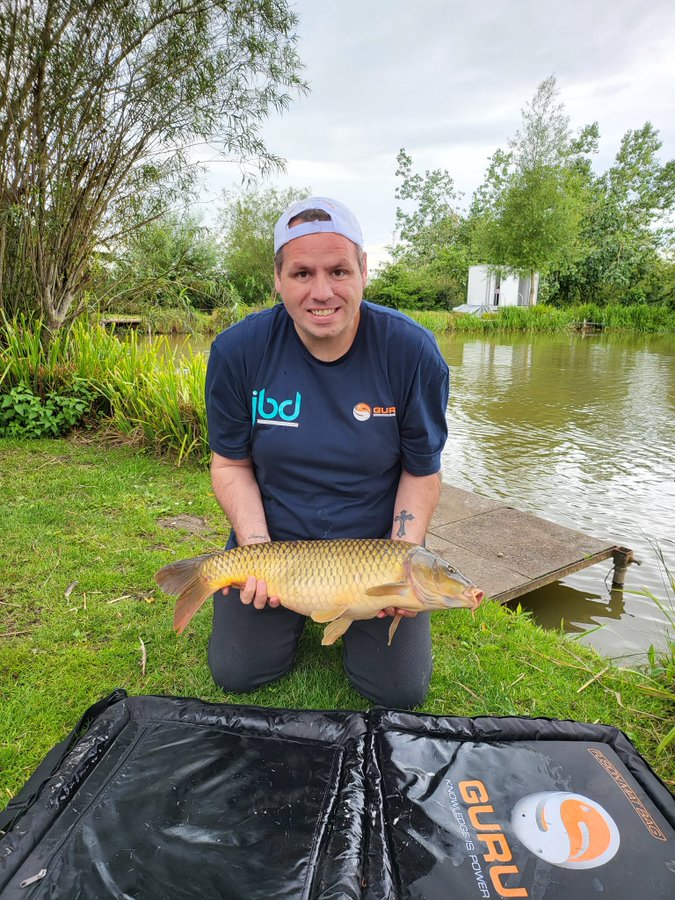 Adrian Lewis, former darts world champion, holding a large carp he caught while fishing.