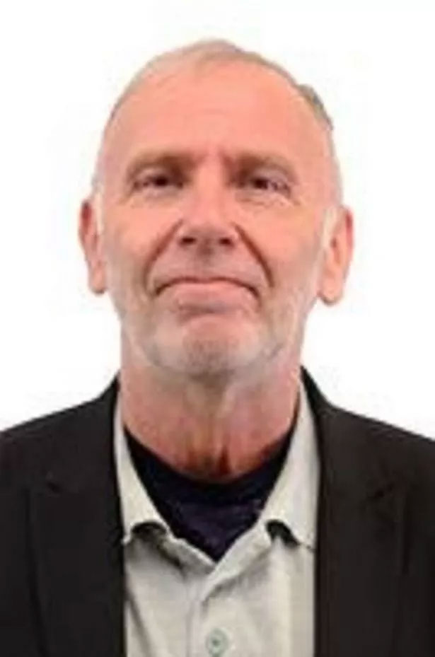 a man with a beard is wearing a suit and smiling for the camera .