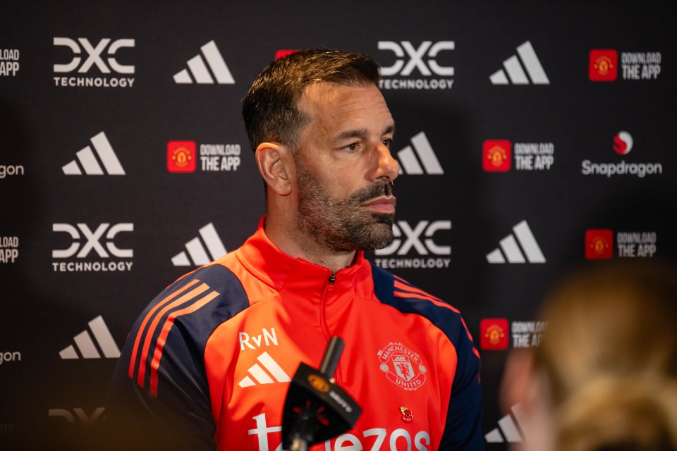 a man wearing a red adidas jacket is talking into a microphone