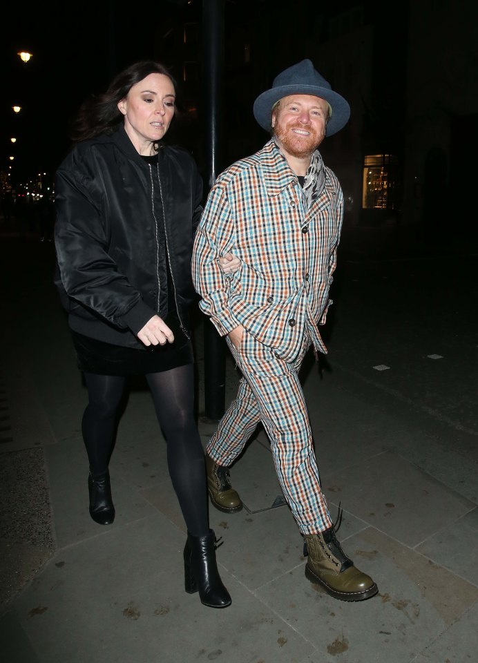 a man in a plaid suit is walking with a woman
