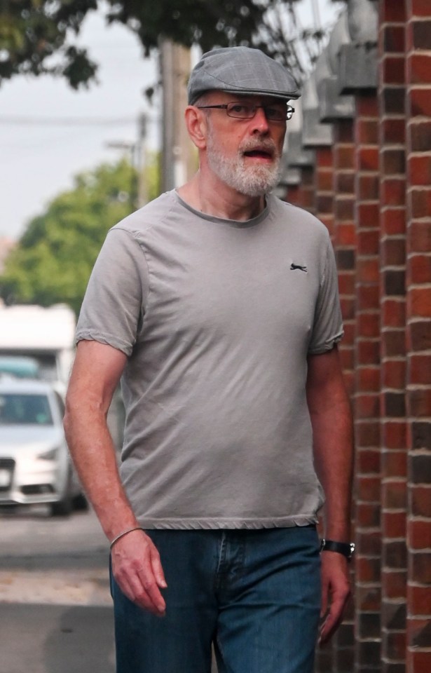 a man wearing a slazenger t-shirt is walking down the street