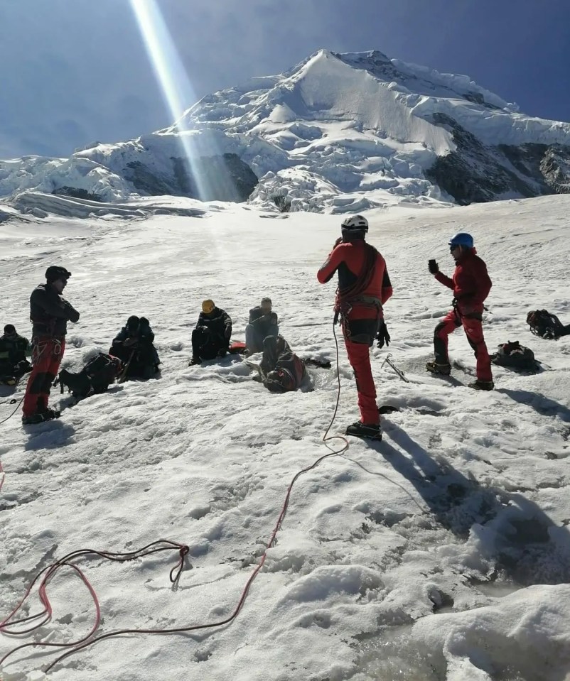 a group of people standing in the snow with a mountain in the background