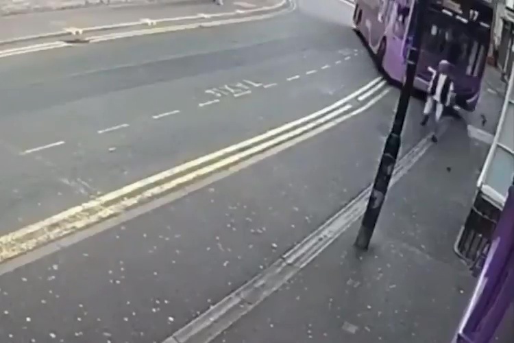 a person is walking down a street next to a bus .