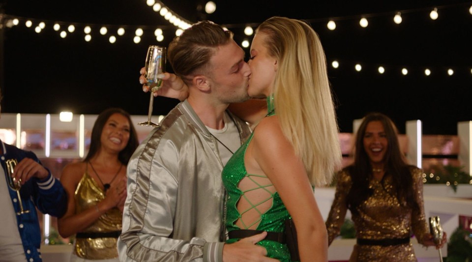 a man and a woman are kissing while holding a glass of champagne