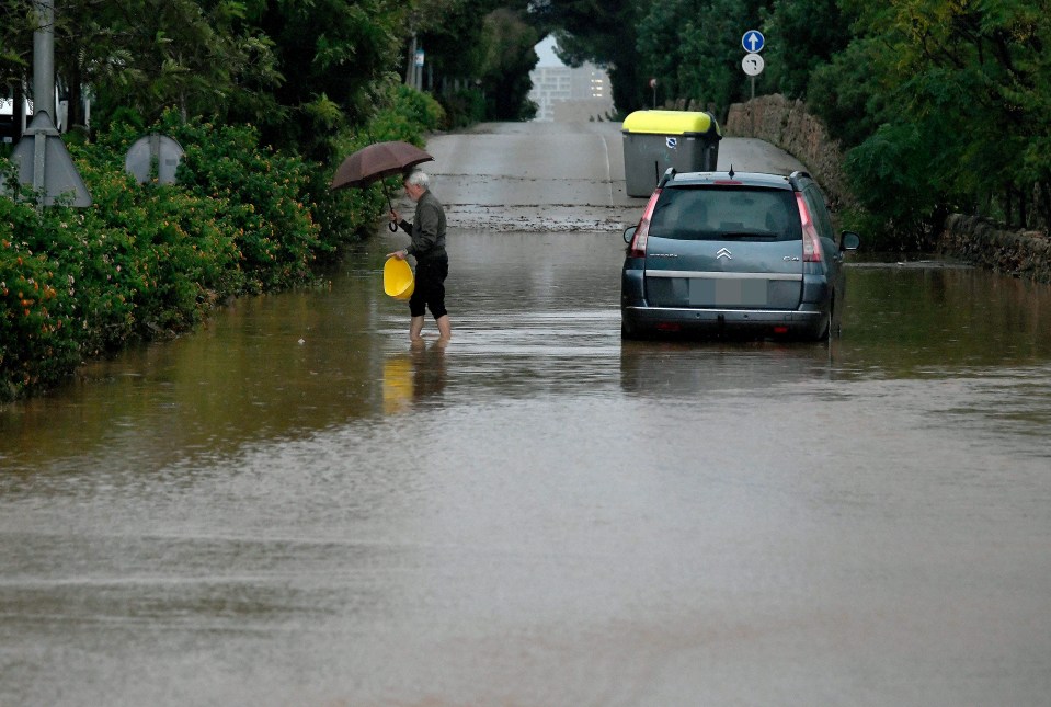 a man with an umbrella walks through a flooded street next to a citroen car