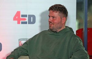 a man sits in front of a sign that says 4ed