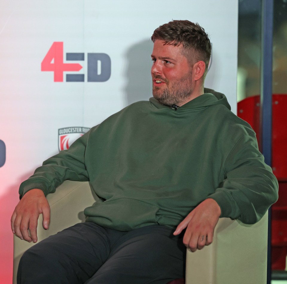 a man sits in front of a sign that says 4ed
