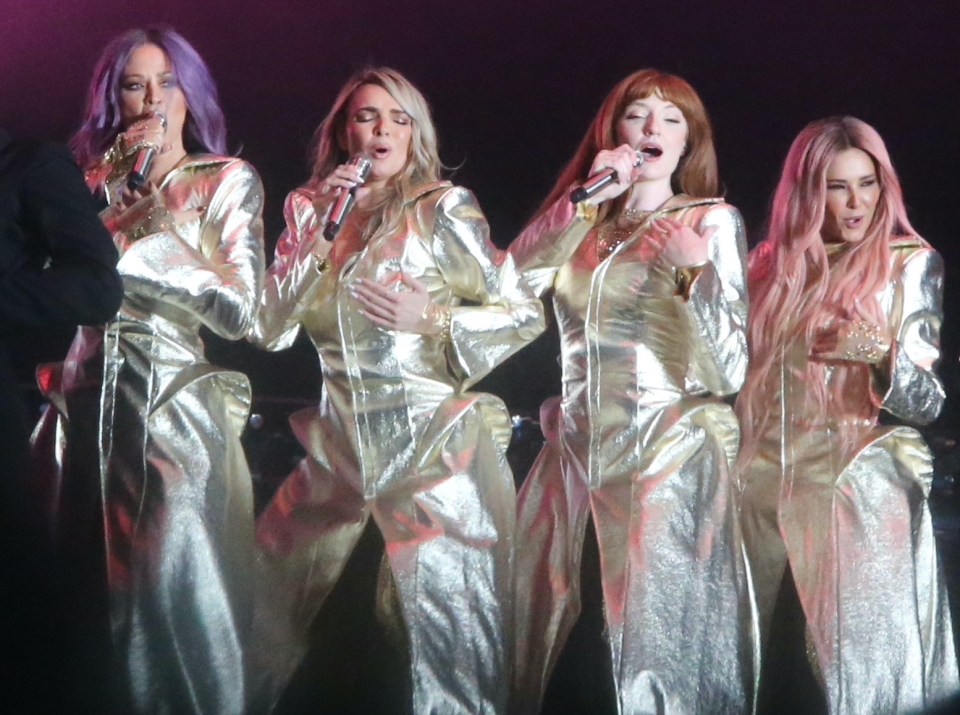a group of women singing into microphones on a stage