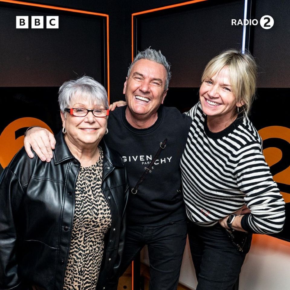 a man wearing a givenchy sweatshirt poses with two women