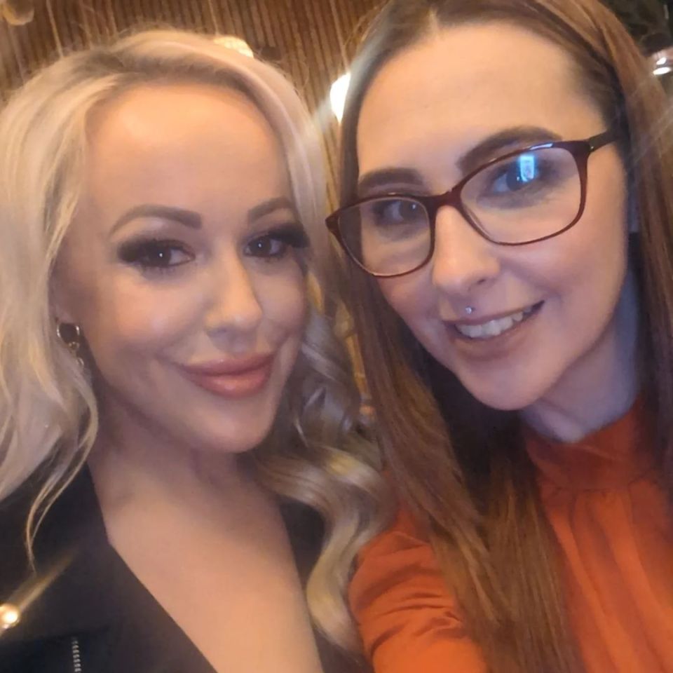 two women posing for a picture with one wearing glasses