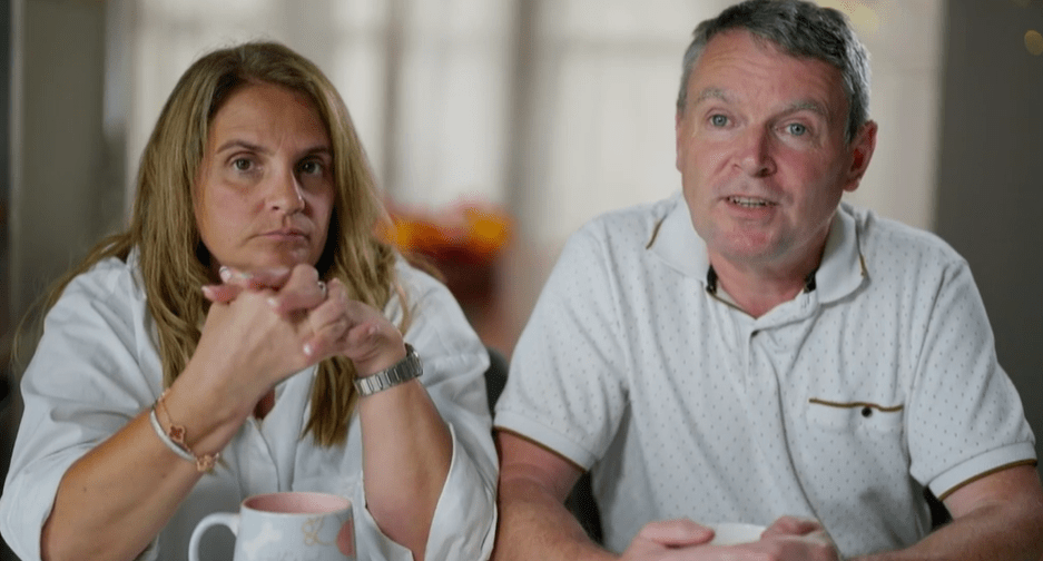a man and a woman sit at a table with their hands folded