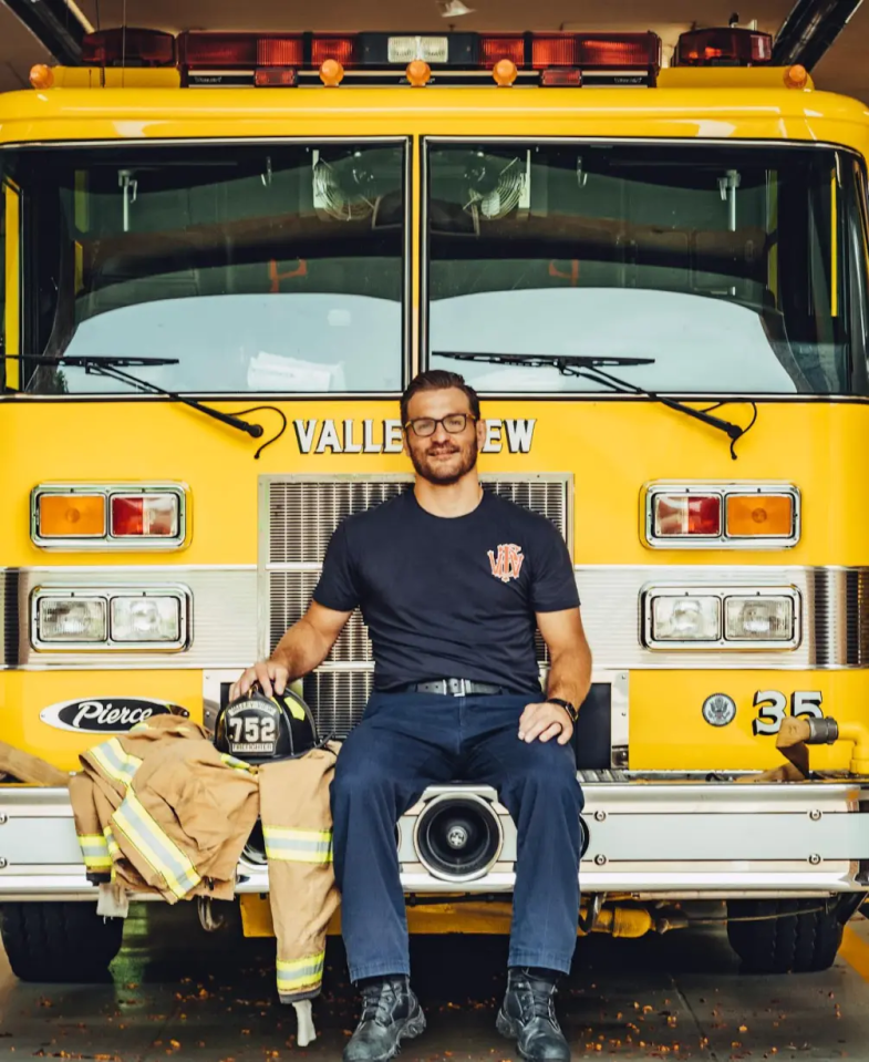 a fireman sits on the front of a yellow valleyview fire truck