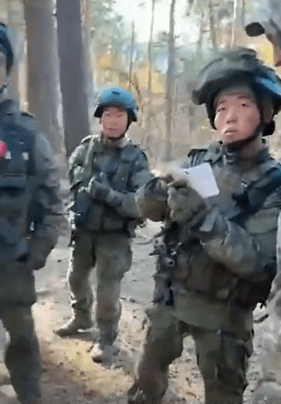 a group of soldiers are standing in the woods and one is holding a piece of paper