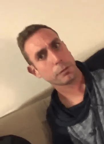 a man is sitting on a couch and making a funny face .
