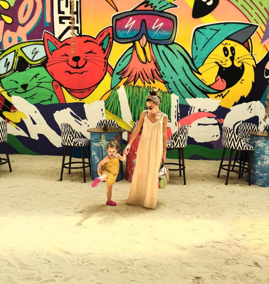 a woman and a little girl are standing in front of a wall that has graffiti on it