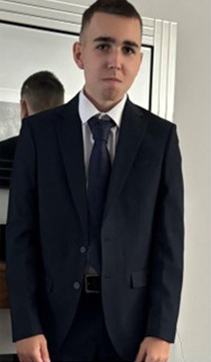 a young man in a suit and tie is standing in front of a mirror .