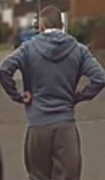 a man in a blue hoodie is standing with his hands on his hips .