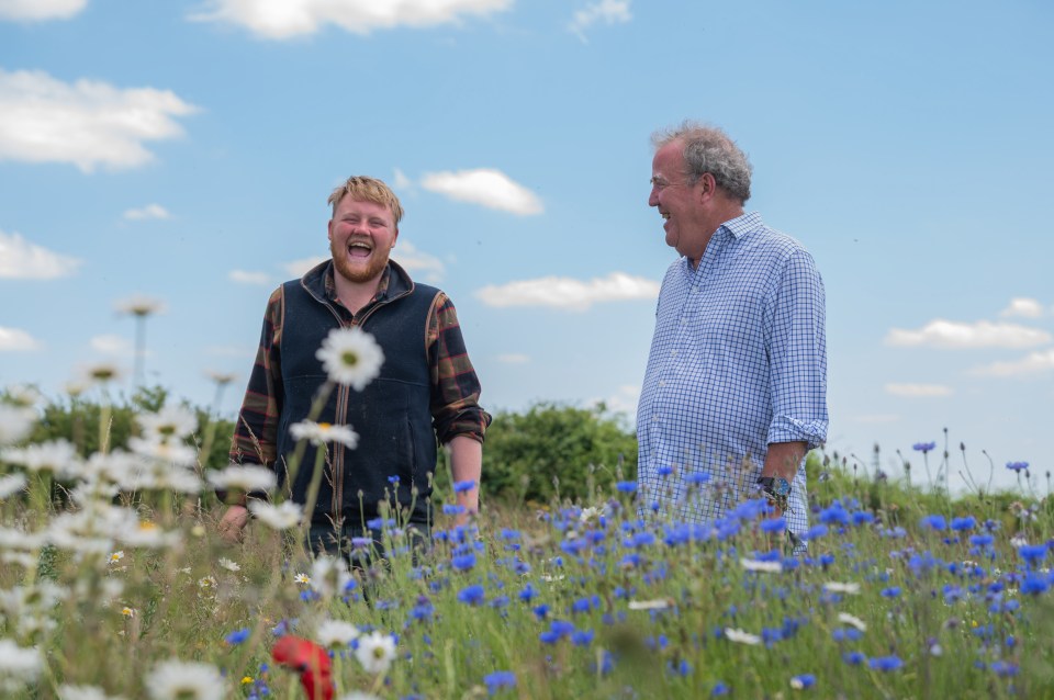 two men standing in a field of flowers laughing
