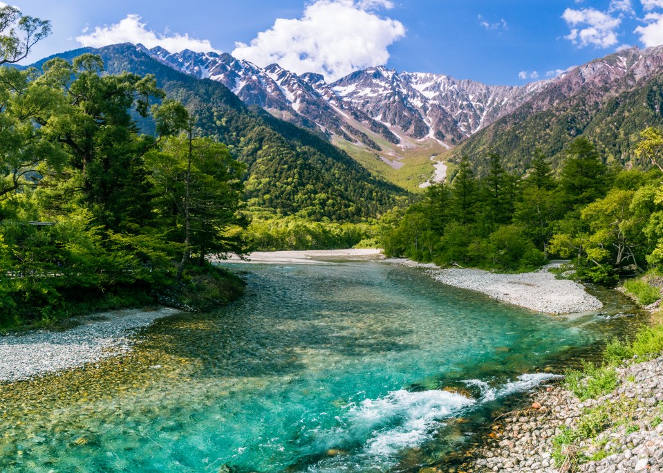 a river flowing through a valley with mountains in the background