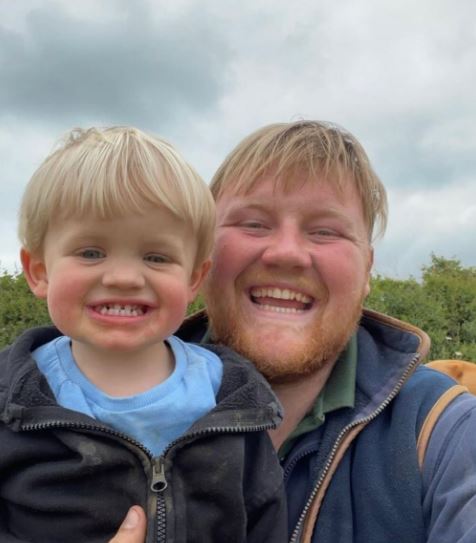 a man with a beard is holding a little boy and smiling .
