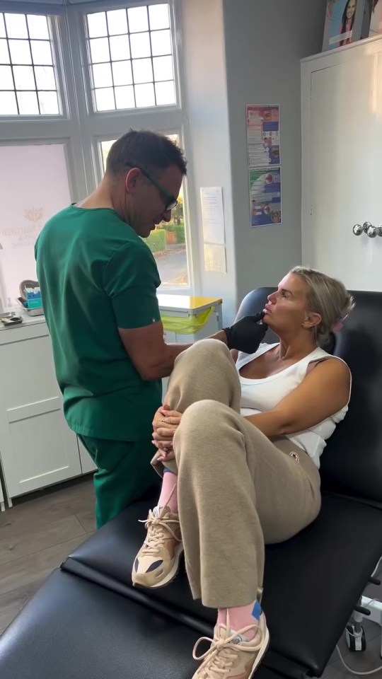 a man in a green scrub is talking to a woman in a chair