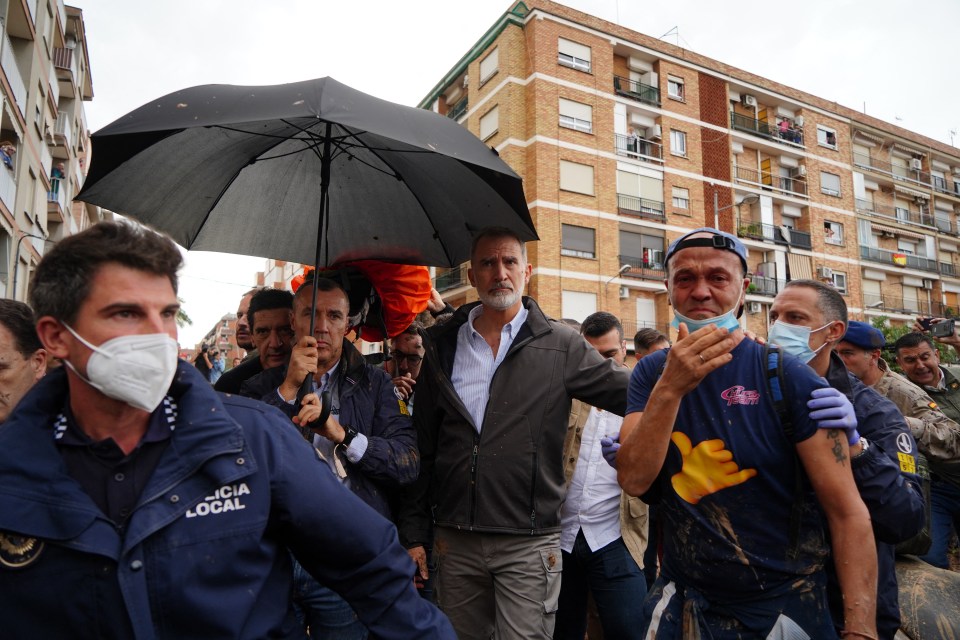 a man in a policia local jacket holds an umbrella
