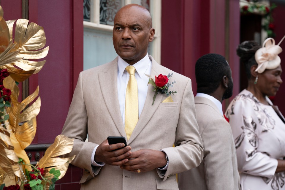 a man in a tan suit has a red rose in his pocket