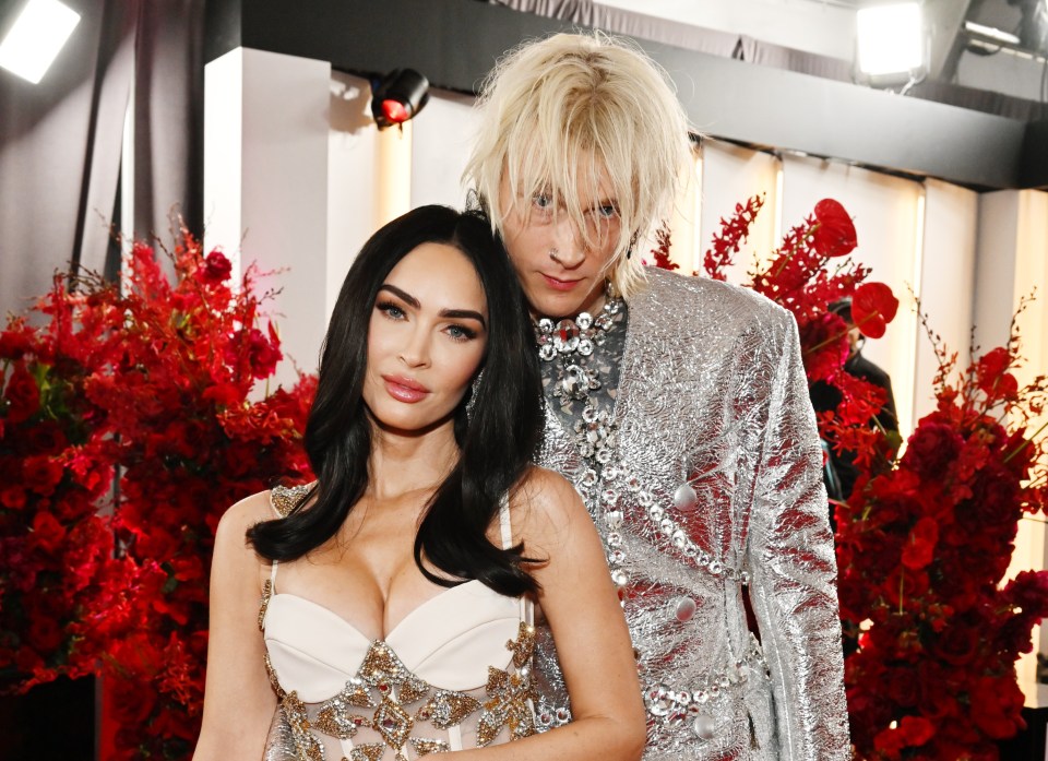 a woman in a white dress stands next to a man in a silver suit