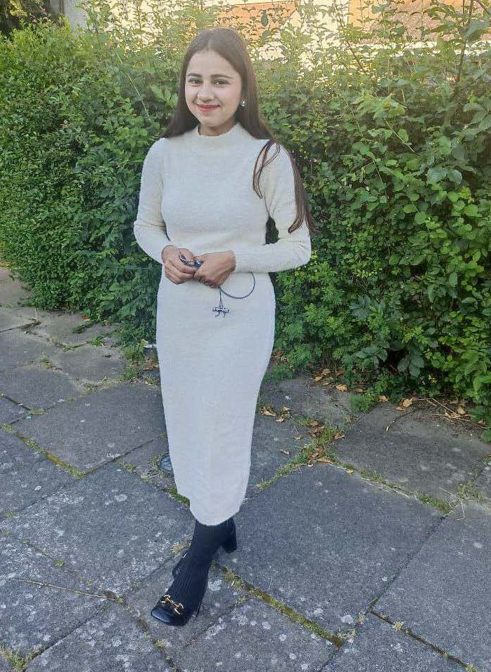 a woman in a white dress is standing on a sidewalk