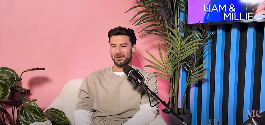 a man sitting in front of a microphone with the words liam & millie behind him