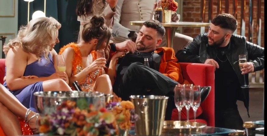 a group of people are sitting on a couch drinking champagne
